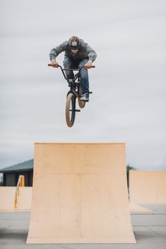 Teenager performing stunt on ramp at skateboard park