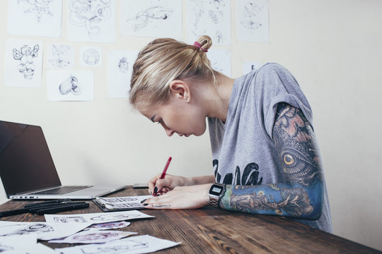Confident tattoo artist working on designs by laptop at art studio