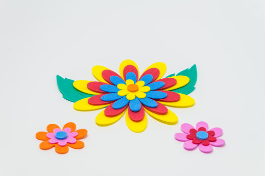 Colorful foam craft flower with green leaf on white background and selective focus