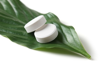 white pill lying on a green leaf