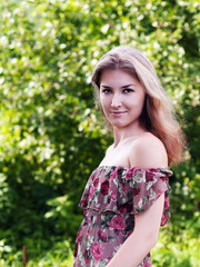 Fototapeta premium Beautiful girl in floral dress stand in garden.
