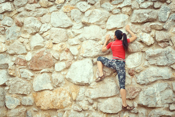 Fototapeta na wymiar happy woman climbs a rock while trekking outdoors