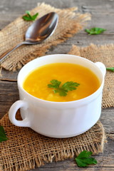 Pumpkin soup with potatoes, rice and parsley. Simple pumpkin soup in bowl on old wooden background, spoon, burlap. Vegetarian dish. Rustic style
