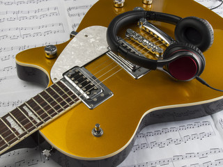 Guitarra eléctrica, partitura y auriculares
