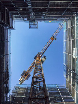 Directly below shot of crane and glass building against clear blue sky