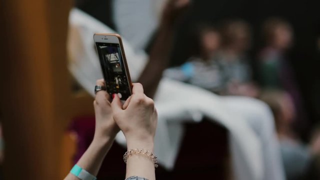 Closeup hands of a girl holding smartphone and taking pictures of a fashion show
