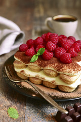 Homemade tiramisu with raspberry on a black plate.