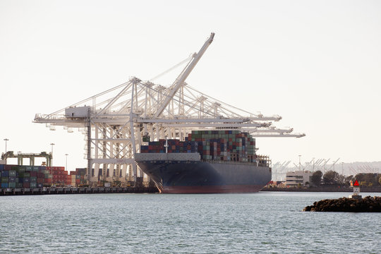 Container ship by cranes moored at sea against sky
