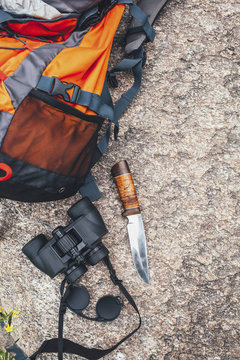 High angle view of backpack with binoculars and knife on rock