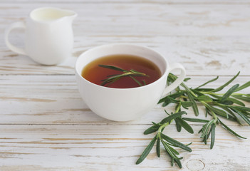 Rosemary tea and milk jar on wooden table.