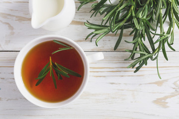 Rosemary tea and milk jar on wooden table.