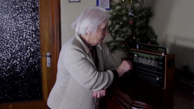 99 Years Old Woman Turning The Buttons Of An Old Radio And Listening