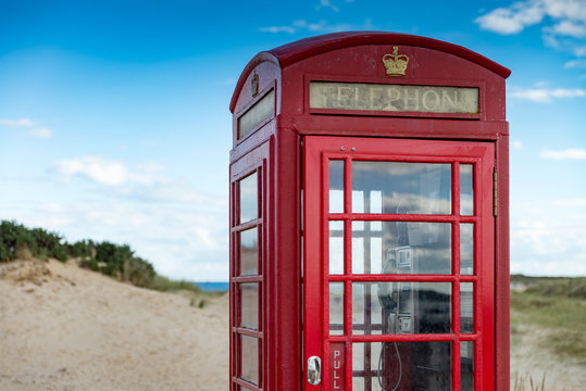 Battered British telephone box on a sandy beach