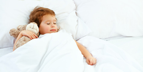 child little girl sleeps in the bed with teddy bear