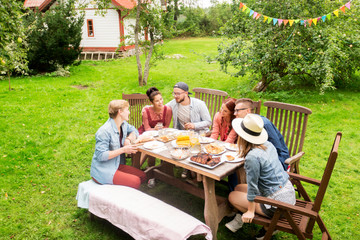 happy friends having dinner at summer garden party