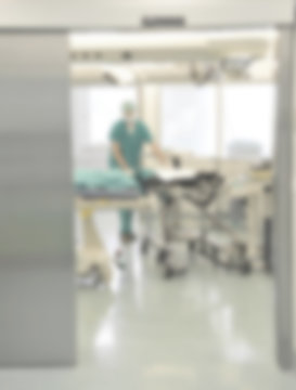 A motion blurred photograph of a patient on stretcher or gurney being pushed at speed through a hospital corridor by doctor