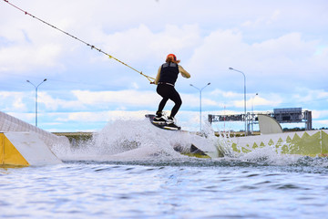 Yong brave boy ride in wakepark on the bord. Extreme sport concept.