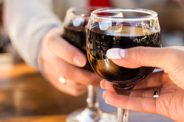 two glasses of wine in the hands of man and woman with a blurred background