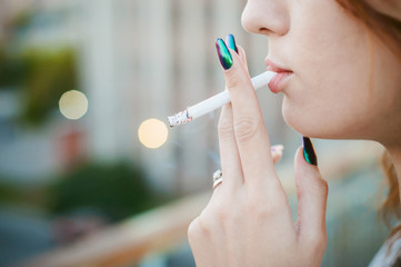 girl with a cigarette. young beautiful woman smokes a cigarette in the street