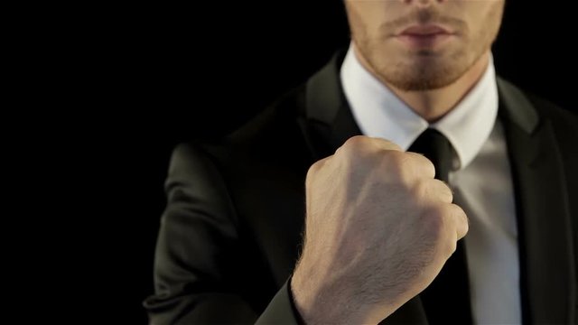 Man in black suite shows his fist