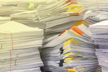 Pile of documents on desk stack up high waiting to be managed