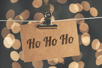 Ho Ho Ho sign pegged to a string with blurred bokeh lights in the background