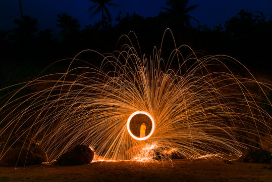 Burning steel wool on the top rock behind beach in twilight time.