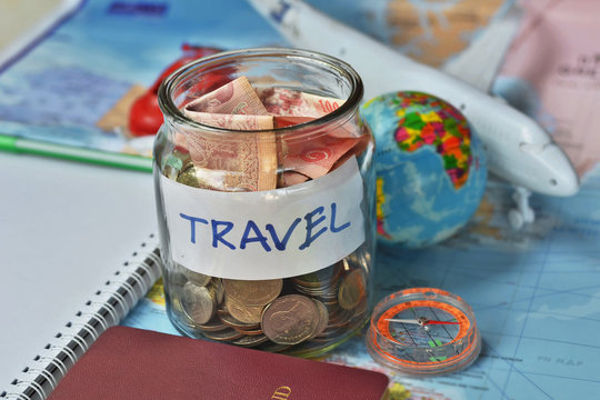 Travel budget concept. travel money savings in a glass jar with compass, passport and aircraft toy on world map