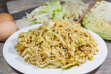 Stir fried noodles with vegetables in brown plate and on wood.