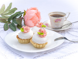 Assorted Fancy Gourmet Cupcakes on a plate. Colorful cupcakes with beautiful decoration over white vintage lace background. Surrounded by flowers and cup of coffee.