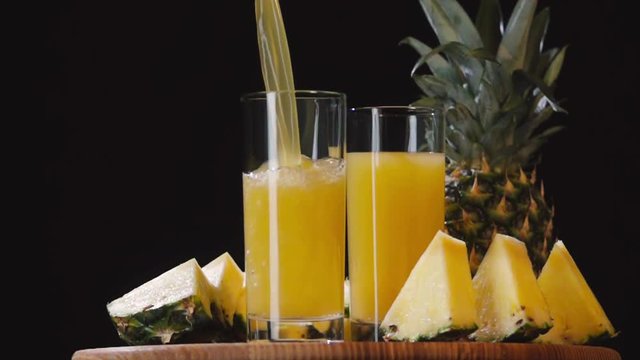 Pouring pineapple juice into glass slow motion HD video. Still life fruits composition isolated on black background
