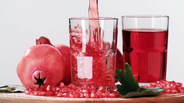 Pouring pomegranate juice into glass slow motion HD video. Still life fruits composition isolated on white background