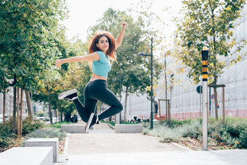 Young sportive woman jumping looking at camera outdoor in the city - athletic, sportive, succesful...