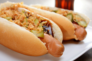 Hot Dogs im Brötchen mit Röstzwiebeln, Gürkchen, Ketchup und Cola 