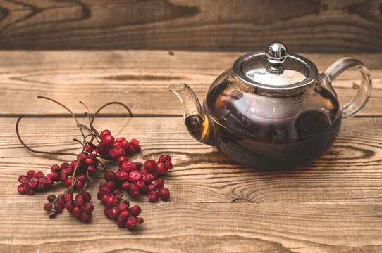 Transparent teapot and Schisandra berries on wooden boards