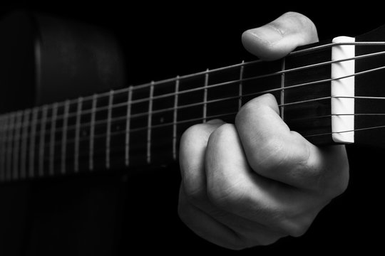 musician left hands playing chord on guitar fingerboard, BW filter for music background
