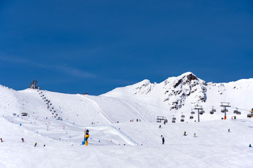 Skiers, chairlift and easy giant slalom course in Alpine ski resort in Solden in Otztal Alps, Tirol, Austria