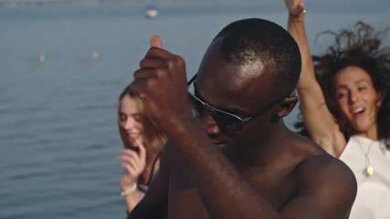 Young African man dancing on the beach surrounded by his friends - Powered by Adobe