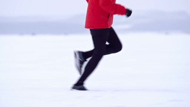 Tracking shot of man running in snow during winter marathon training