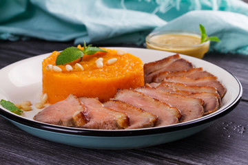 Roast duck breast and pumpkin mash, served with mint and pine nuts. Slices of duck with sweet butter squash, mustard and honey sauce