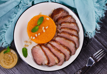 Roast duck breast and pumpkin mash, served with mint and pine nuts. Slices of duck with sweet butter squash, mustard and honey sauce. View From Above, Top Studio Shot