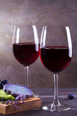 Glasses and bottle red  wine with lavender, pesto cheese and grape on chopping board. Wine and food still life