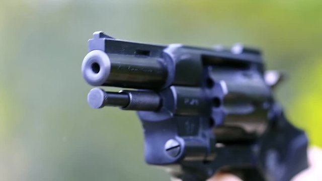 Man shoots a revolver with sound. Man cocks and shoots. Soldier shoots a pistol. Man with black gun, raise the cock, cock the gun, close up