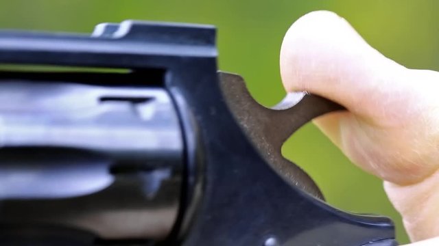 Man cocks and shoots. Man shoots a revolver. Soldier shoots a pistol. Man with black gun, raise the cock, cock the gun, close up