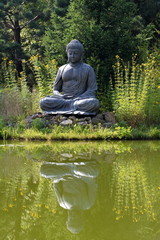 Friede, großer sitzender Buddha spiegelt sich im Gartenteich