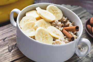 Oatmeal porridge with banana and cinnamon in bowl, close up view