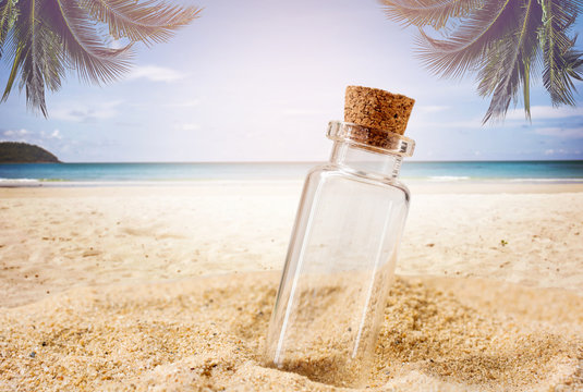 empty bottle over tropical sand beach with clear blue sky background for travel on vacation summer concept.