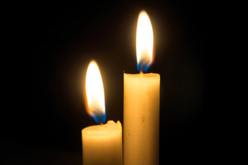 Two burning candles on black background. Copyspace