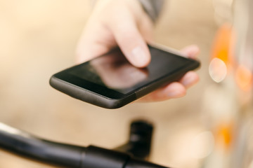 Woman with bicycle using mobile phone outdoors