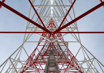 Newly completed telecommunication tower with white and red paint, step ladder